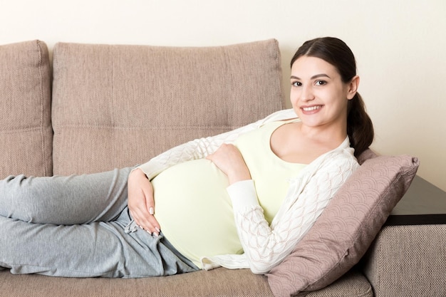 Une femme enceinte se détend chez elle sur le canapé.