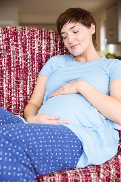 Femme enceinte se détendre sur le canapé