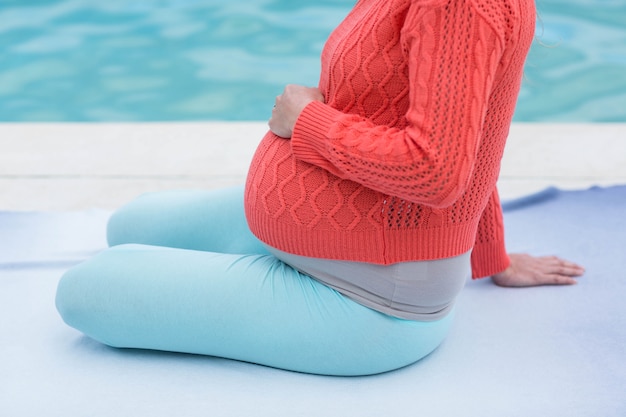 Femme enceinte se détendre à côté de la piscine