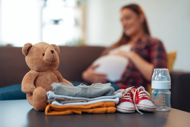 Une femme enceinte se prépare pour la maternité, emballant des affaires pour bébé. prépa femme enceinte