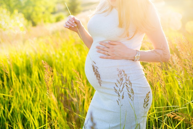 Une femme enceinte se promène dans le champ