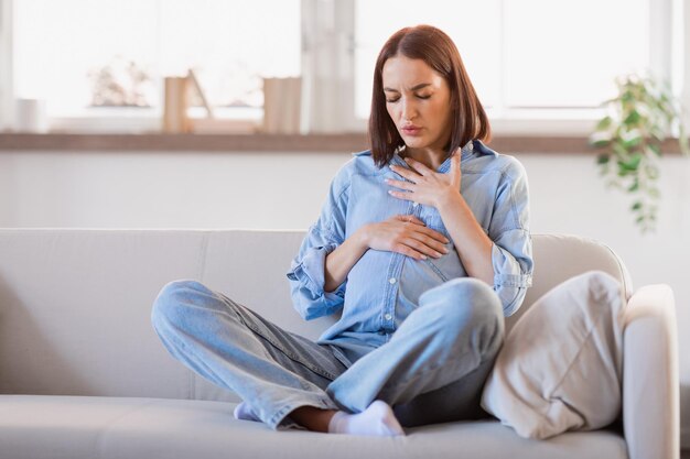 Photo une femme enceinte se sent mal en touchant son ventre et sa poitrine à la maison.