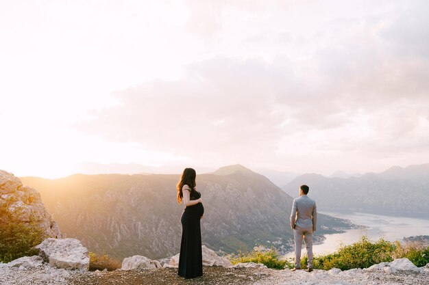 Une femme enceinte se tient à côté d'un homme au sommet d'une montagne