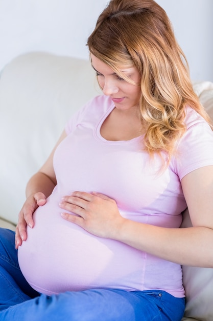 Femme enceinte, séance, sur, divan, toucher, elle, ventre