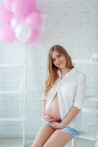 femme enceinte en short en jean et une chemise blanche