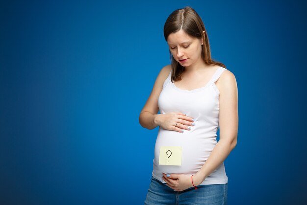 Femme enceinte avec signe de question sur son ventre comme symbole du sexe d'un bébé