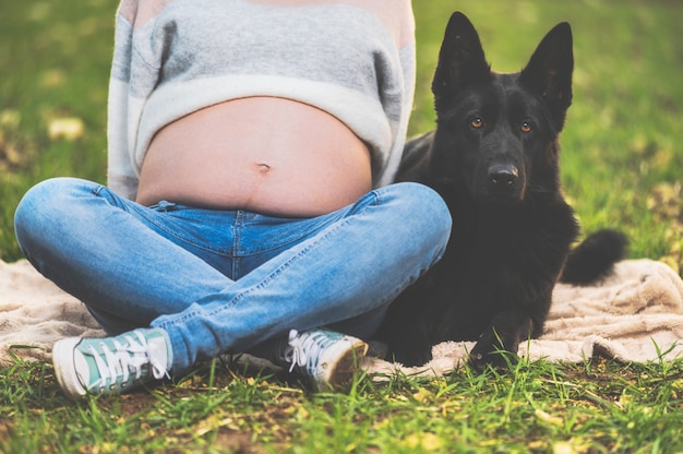 Femme enceinte et son chien allongé dans le parc.