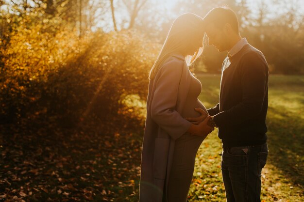 Femme enceinte et son homme affectueux posant au parc d&#39;automne