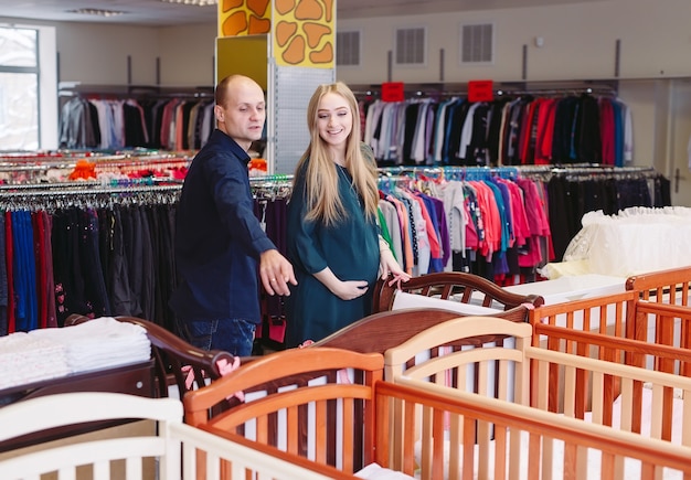 Une femme enceinte avec son mari choisit un lit bébé dans le magasin.