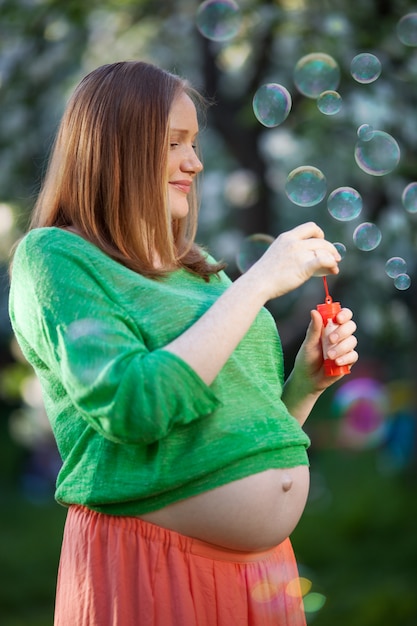 Femme enceinte en soufflant des bulles en plein air