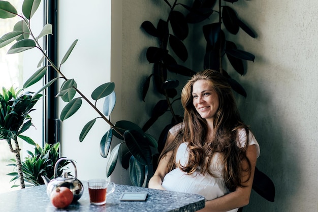 Une femme enceinte souriante assise au café.