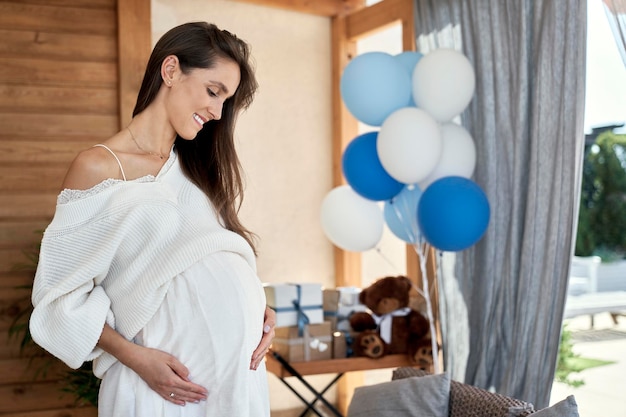 Photo une femme enceinte souriante avec des décorations bleues à l'extérieur
