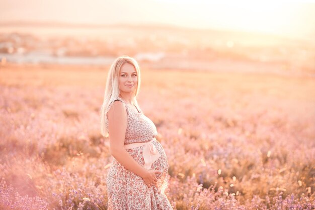 Femme enceinte souriante posant dans un champ de lavande