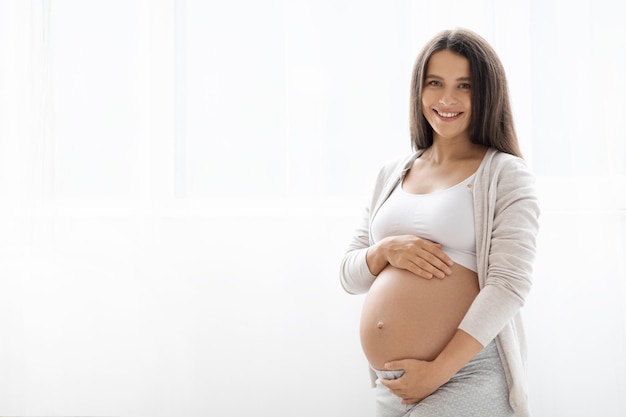 Femme enceinte souriante posant sur fond blanc