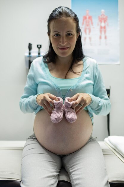 Photo une femme enceinte tenant des chaussures de bébé à l'hôpital