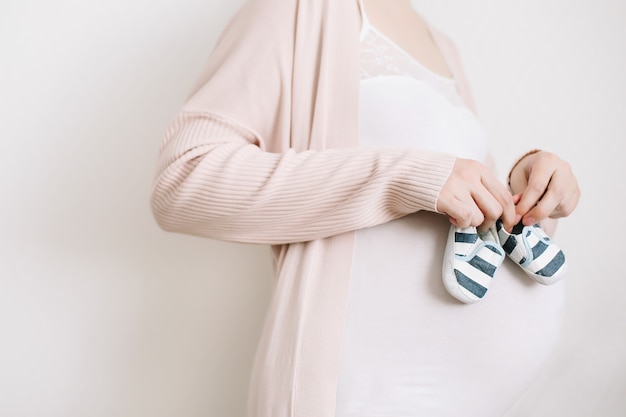 Femme Enceinte Tenant Des Chaussures Pour Le Nouveau-né