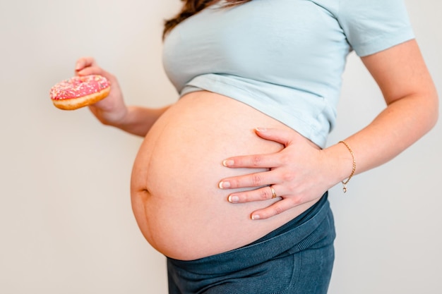 Femme enceinte tenant un concept de régime de beignet et diabète sucré gestationnel chez les femmes enceintes