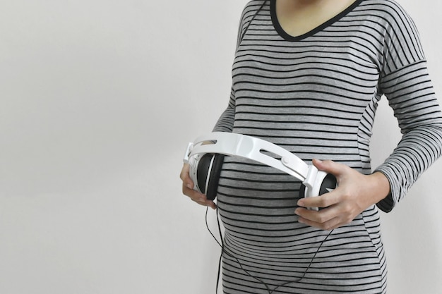 Femme enceinte tenant des écouteurs sur le ventre