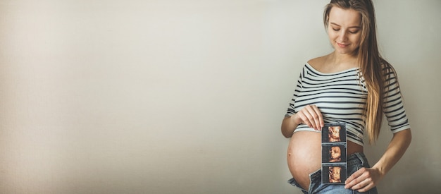 Femme enceinte tenant l'image de l'échographie. Concept de grossesse, soins de santé, gynécologie, médecine. Jeune maman attend le bébé.