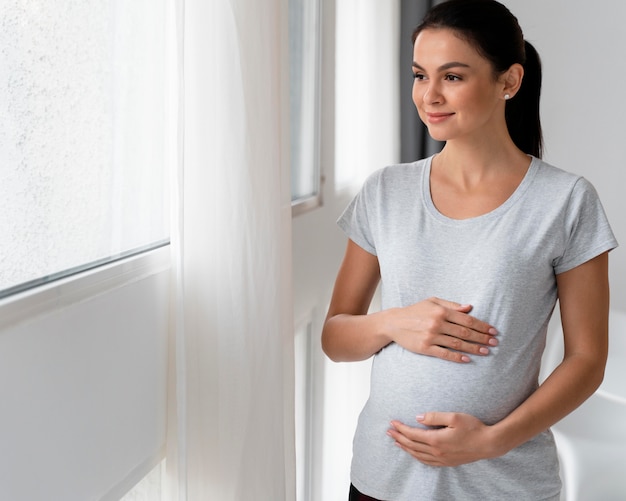 Femme enceinte tenant son ventre avec espace copie