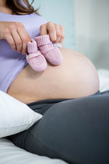 Femme enceinte, tenue, chaussures bébé, bosse, dans, chambre à coucher