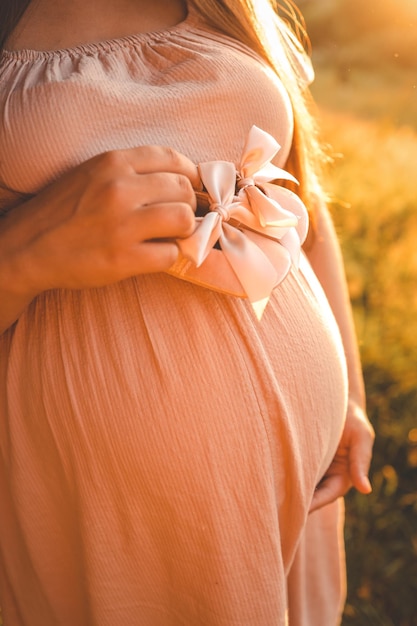 Photo une femme enceinte tient de jolies chaussures de bébé dans ses mains le concept d'attendre un bébé