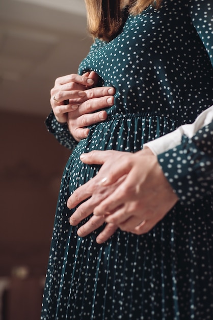 Une femme enceinte tient les mains de son mari sur son ventre