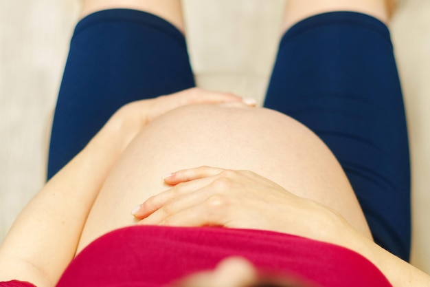 Femme enceinte tient ses mains dans son estomac Troisième trimestre Grossesse pour un miracle Maternité