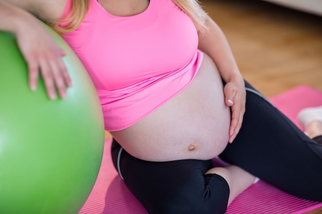 Femme enceinte en touchant son ventre à côté de ballon d&#39;exercice