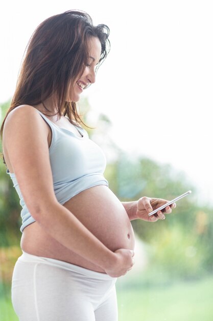 Femme enceinte, toucher, ventre, textos, devant, a, fenêtre