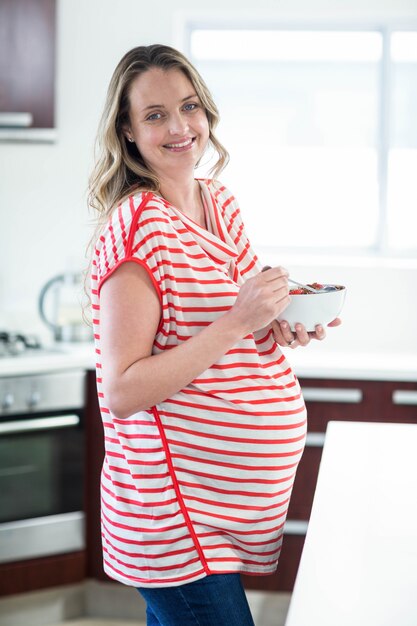 Femme enceinte en train de manger des céréales dans la cuisine