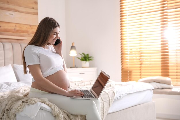 Femme enceinte travaillant sur le lit à la maison espace pour le texte Congé de maternité