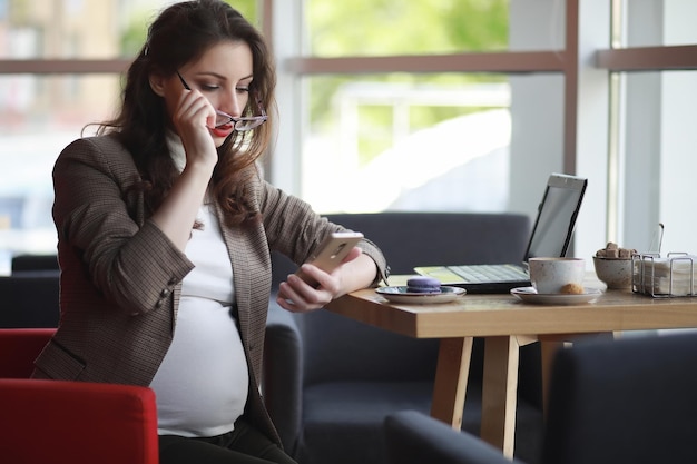 Femme enceinte travaillant sur ordinateur au café