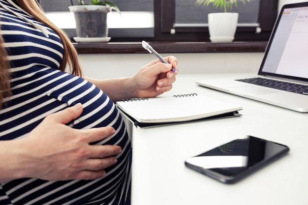 La femme enceinte travaillant avec ordinateur portable