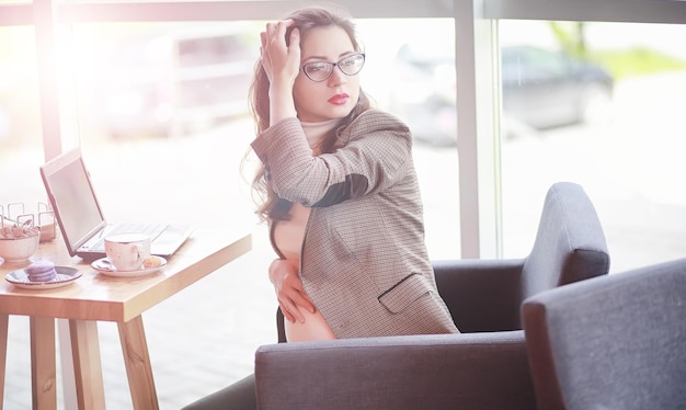 Femme enceinte travaillant pendant le déjeuner sur l'ordinateur au café