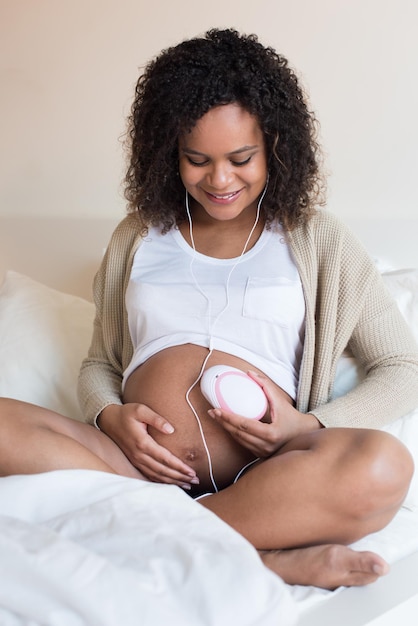 Femme enceinte utilisant un doppler fœtal à la maison