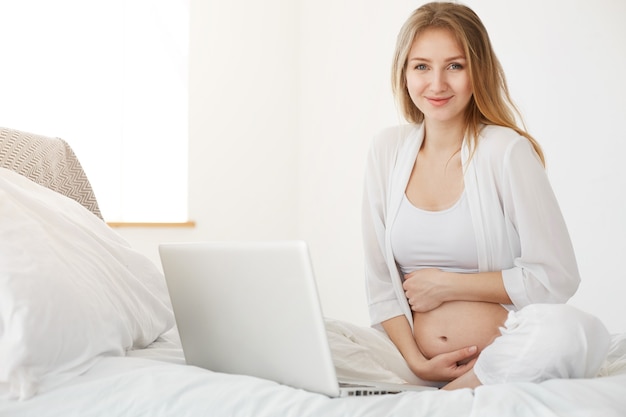 Femme enceinte utilisant un ordinateur portable à la maison. Entrepreneur en ligne gérant sa boutique en ligne de vêtements pour enfants