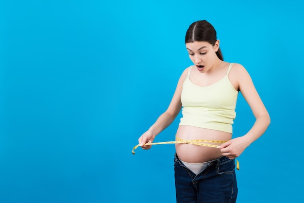 Femme enceinte utilisant un ruban à mesurer pour vérifier le développement du bébé et la croissance du ventre