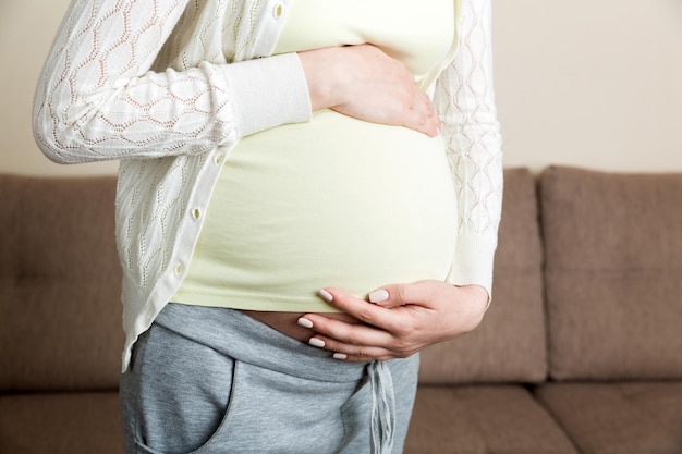 Femme enceinte avec ventre douloureux sur le canapé à la maison