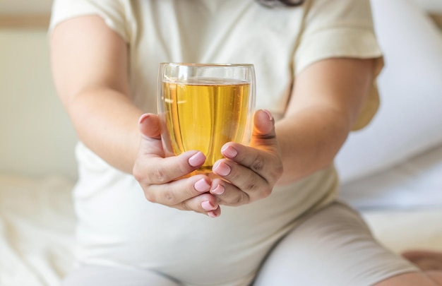 femme enceinte avec un verre de bière dans les mains. une femme tient un verre de bière et une autre main sur le ventre