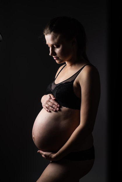 Femme enceinte vêtements noirs fond sombre