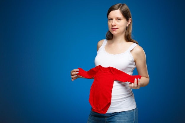 Femme enceinte avec des vêtements de nuit rouges pour bébé le concept de la douche de bébé avec un espace libre pour le texte