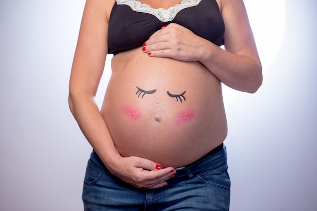 Femme enceinte avec un visage tendre dessiné sur son ventre