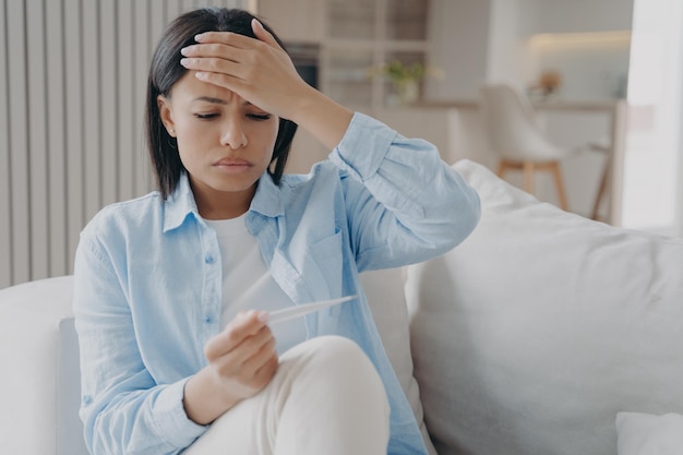 Une femme endormie malade examine la température et touche la tête Fatigue due à une infection virale