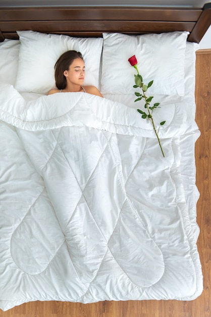 Photo la femme endormie avec une rose sur le lit. vue d'en-haut