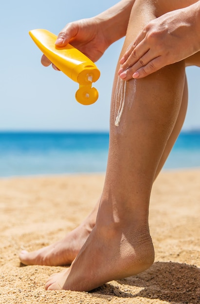 Une femme enduit ses pieds avec de la crème solaire
