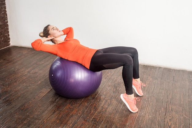 Femme d'énergie équilibrant et faisant de l'exercice dans un ballon de fitness