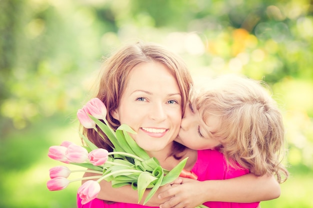 Femme et enfant avec bouquet de fleurs sur fond vert flou Concept de vacances en famille de printemps Journée de la femme