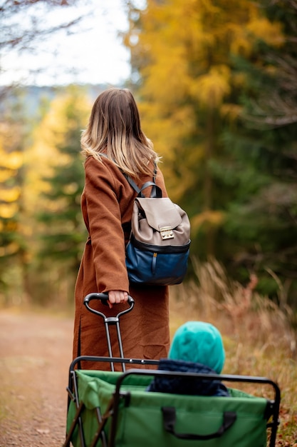 Femme avec un enfant dans un chariot descendant dans la forêt