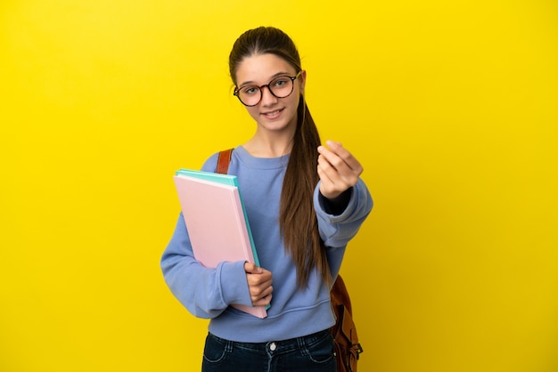 Femme enfant étudiant sur fond jaune isolé faisant un geste d'argent